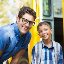 Aws Teacher And Young Male Student Smiling At The Door Of A School Bus