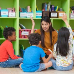 Enthused Kids Sitting In Half Circle Around Teacher Copy